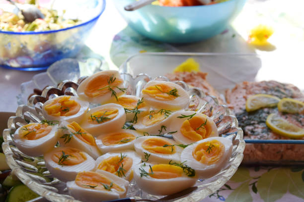 Traditional Swedish smorgasbord during Easter holiday with healthy boiled eggs cut in half, decorated with some fresh dill and cooked salmon in the background on the table.
