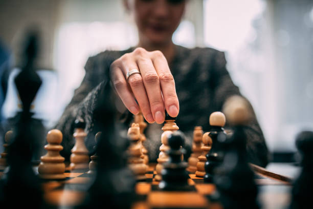 mujer jugando ajedrez - juego de ajedrez fotografías e imágenes de stock