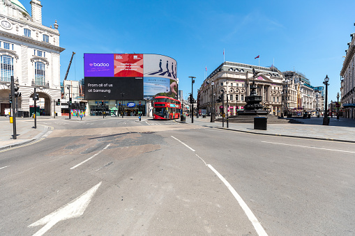 Empty Piccadilly circus in London during lockdown, one red double decker bus only on the street