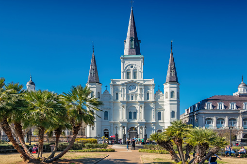 People enjoy a sunny day on Jackson Square in front of the landmark St. Louis Cathedral in New Orleans Louisiana USA.