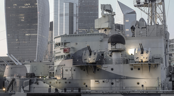 London, England - Apr 20, 2019 : Close-up of The retired Royal Navy light military cruiser or HMS Belfast which saw battle in WWII and is now a museum ship moored on the River Thames in the very center of London at evening. No focus, specifically.