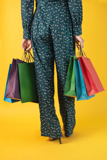 back woman in green pants holding multicolored shopping bags - fashion fashion model asian ethnicity tall imagens e fotografias de stock