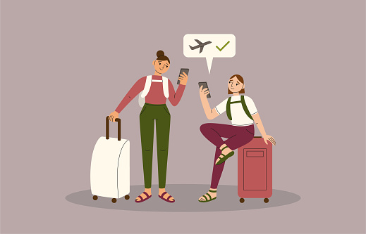Two happy mixed race female friends check into their flight via their mobile smartphone with baggage, backpacks and suitcases.