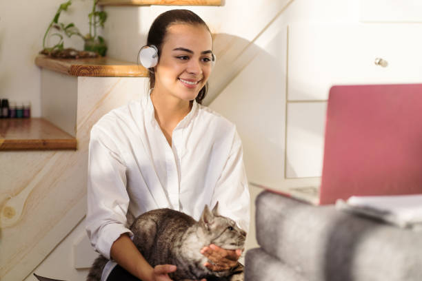 istock Joyful woman petting her cat while watching and online class at home 1294723172