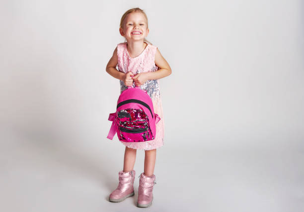 cute little girl with bunny ears backpack in pink sequin dress. childhood, education and people concept - happy kid girl with school bag over grey background - blond hair carrying little girls small imagens e fotografias de stock