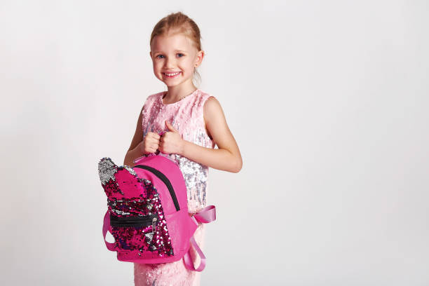cute little girl with bunny ears backpack in pink sequin dress. childhood, education and people concept - happy kid girl with school bag over grey background - blond hair carrying little girls small imagens e fotografias de stock