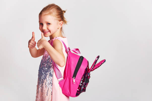 cute little girl with bunny ears backpack in pink sequin dress. childhood, education and people concept - happy kid girl with school bag over grey background - blond hair carrying little girls small imagens e fotografias de stock