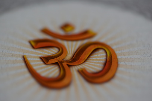 Close up image of the OM AUM symbol in orange color with white background, shot in landscape composition