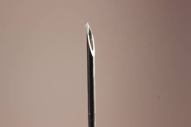 istock Water drop falling from the syringe needle against grey background 1294740155