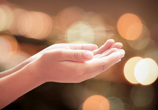 Children hands praying over abstract blurred spiritual light background