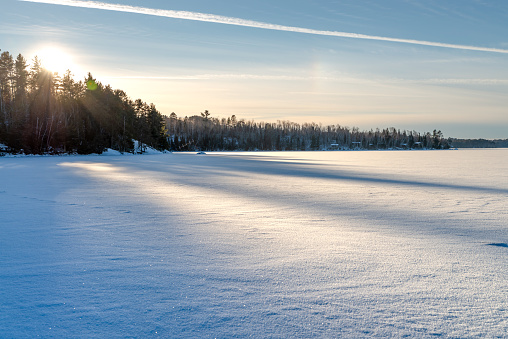 Frozen lake shore and surface covered with snow on sunset in a good weather day