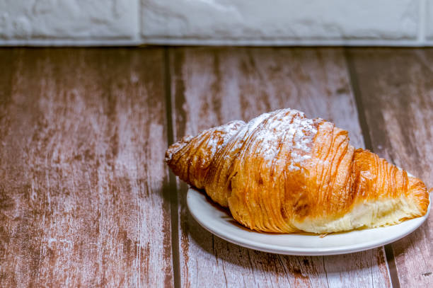 istock Croissants sprinkled with icing sugar in a white plate on a wooden table. 1294752438
