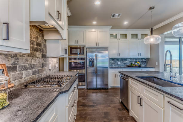Brick look on backsplash and pull out faucet with stainless steel appliances in background