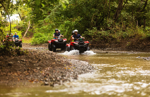 Group of tourists driving quad bikes vehicles thru a creek in Central America