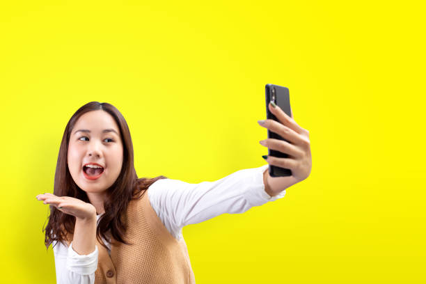 istock Happy pretty girl makes self-portrait on the smartphone over yellow background. 1294777708