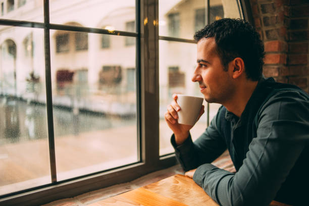 istock Smiling Hopeful Man Looking Out the Window 1294782055