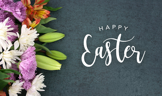 Happy Easter typography over blackboard background with colorful flower blossom bouquet