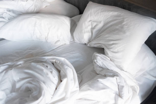 istock Messy bed, white pillow with blanket lying on bed unmade, oversleeping concept 1294787890
