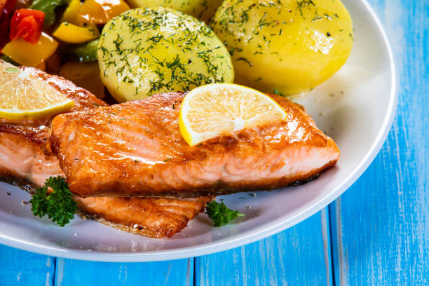 Fried salmon fillet and vegetables served on wooden table