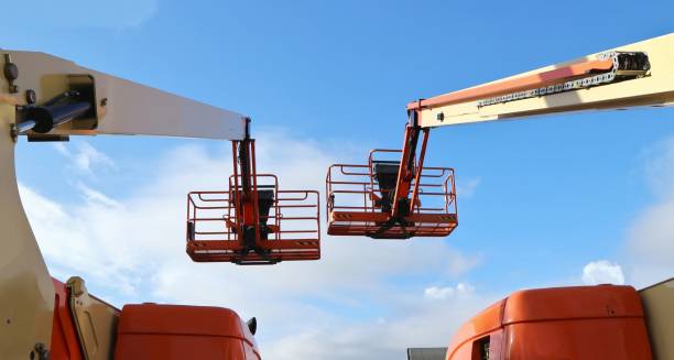 istock Back view of two aerial work platforms against blue sky with clouds. 1294807412