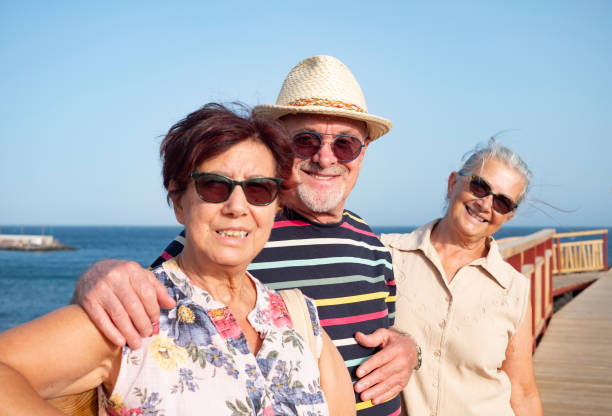 istock A smiling group of three elderly people looking at camera enjoying the seaside excursion standing in a wooden footpath. Active lifestyle for three retirees 1294809255