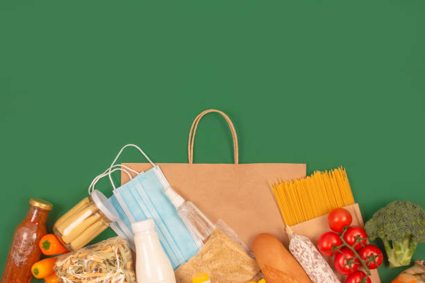 istock Composition with food and medicines donations on green background with copy space for text - pasta, fresh vegatables, canned food, baguette, cooking oil. Food bank concept. Flat lay, selective focus 1294813175