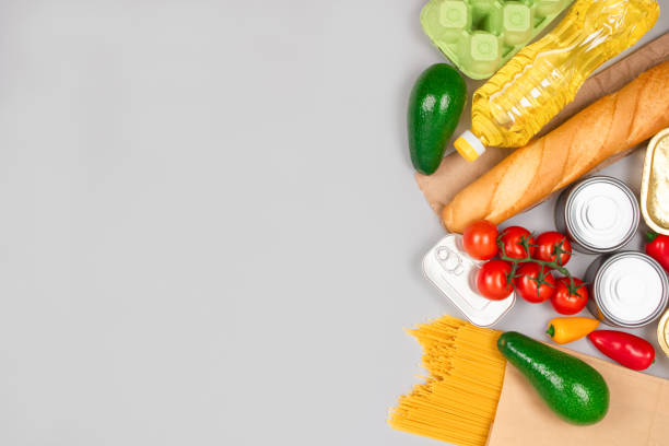 istock Flat lay composition with food donations on gray background with copy space for your text - pasta, fresh vegatables, canned food, baguette, cooking oil. Food donation and food bank concept 1294813181
