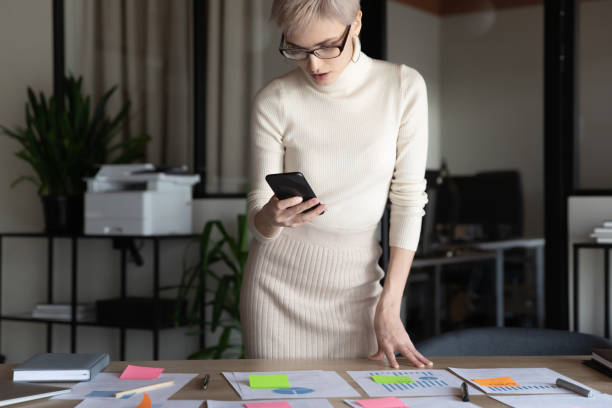 istock Confident businesswoman wearing glasses using phone, working with project statistics 1294818733