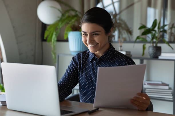 istock Smiling Indian businesswoman using laptop, checking financial documents 1294818746