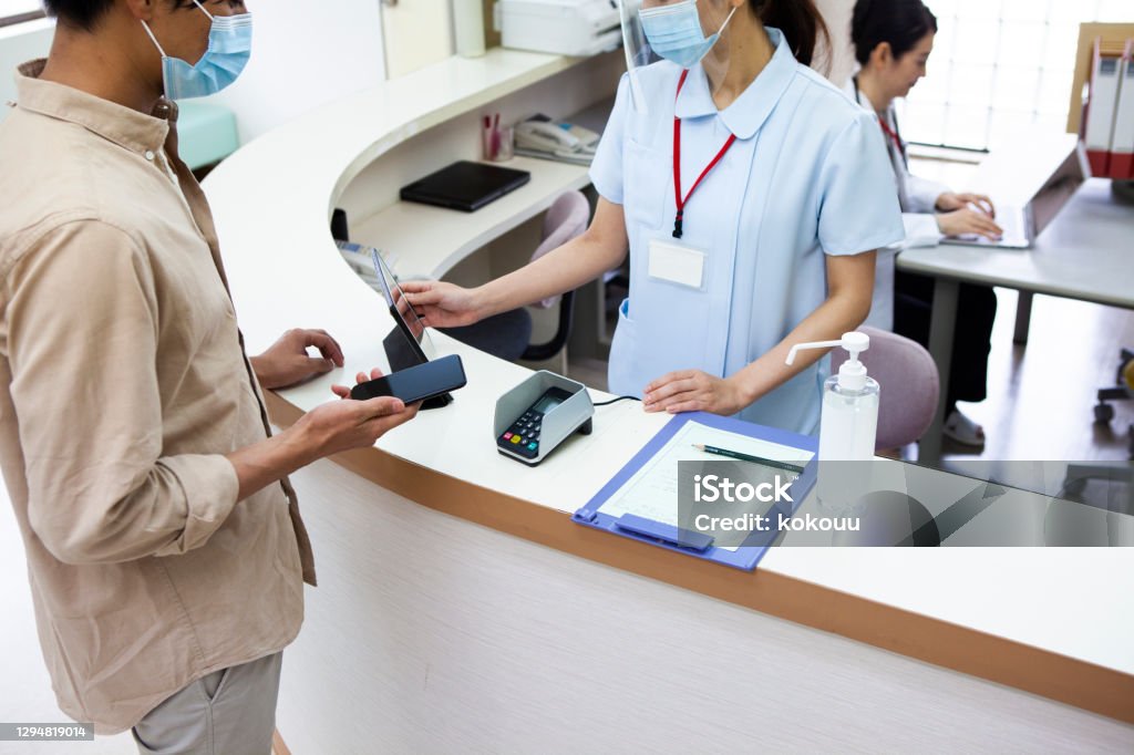A man paying at a hospital using a smartphone Paying Stock Photo