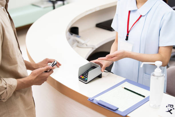 un hombre pagando en un hospital usando un teléfono inteligente - healthcare and medicine receptionist paying credit card fotografías e imágenes de stock