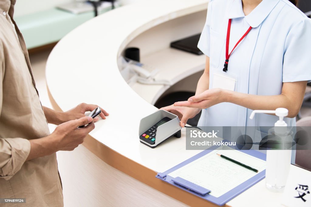 A man paying at a hospital using a smartphone Paying Stock Photo