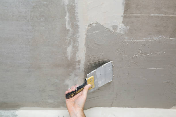 istock Young adult man hand using spatula and plastering ceiling with putty. Closeup. Repair work of home. 1294824051