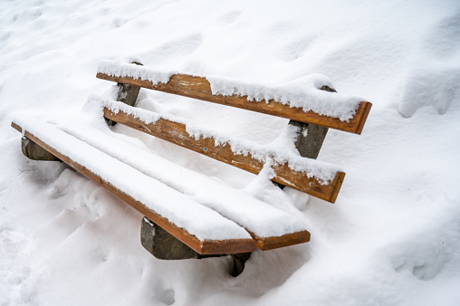 Snow covered bench. Deep snow in winter. Tranquil scene. Les Pleiades, Switzerland.
