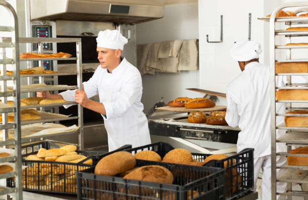 Male baker carrying rack trolley with bread