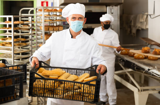 istock Portrait of baker in protective mask with fresh bread at bakery 1294825519