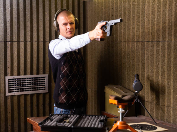 istock Man aiming smallbore sporting pistol at target in shooting range 1294825746