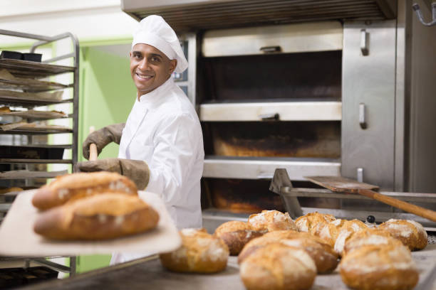 istock man in chefs uniform with bread on shovel in bakery 1294825881