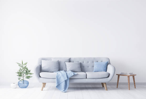 istock Bright room interior mockup for grey and light blue couch, beside wooden coffee table with books on it. Blue glass vase with green plant on the other side 1294828509