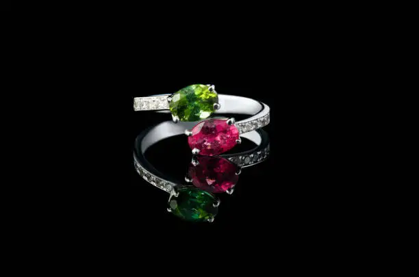 beautiful gold ring with precious stones ruby, chrysoprase, diamonds on a black background close-up