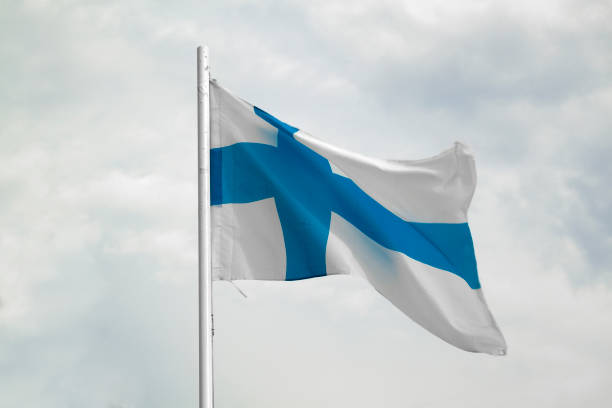 istock Flag of Finland on a blue sky with clouds background 1294840379