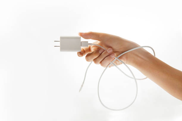 Hand holding a power plug smartphone white background stock photo