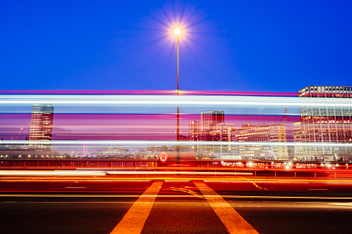 Long exposure blurred motion of vehicles moving past camera on Vauxhall Bridge spanning River Thames in Central London.