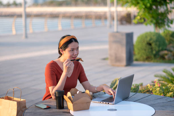 istock Girl having lunch while working remotely outdoors in a park by the seaside. 1294858072