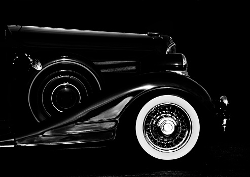 low light, close shot of front half, white wall tire highlighted, chrome highlighted, antique from the 30's, no people, vintage