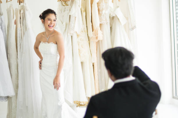 istock Groom sitting and look his Bride trying dresses 1294862994