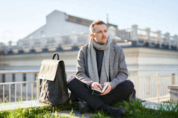 istock Young man on a roof sitting and thinking, holding notes 1294864437