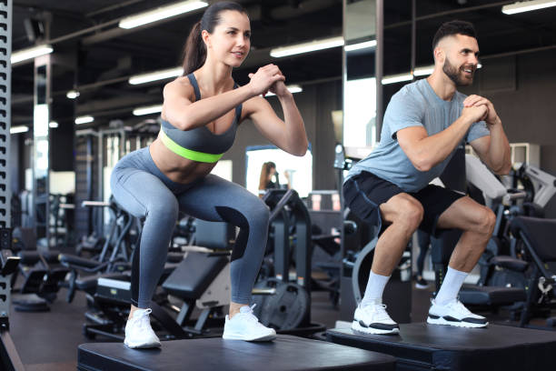 istock Fit couple doing jumping squats in gym gym. 1294866497