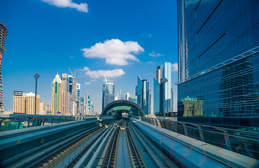 Dubai, UAE - December 5. 2019 - tracks to the metro station in Dubai. The metro is a fast, inexpensive transportation in Dubai. The golden roofs of the stations are visible from afar. In the background the downtown of Dubai with Burj Khalifa and Sheik Zayed Road
