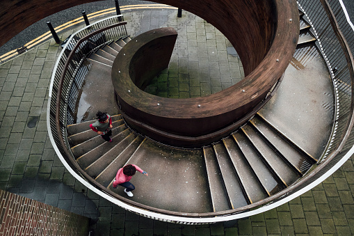 Aerial view of women friends running together getting fit during lockdown. They are in Newcastle City Centre running on a spiral outdoor staircase.
